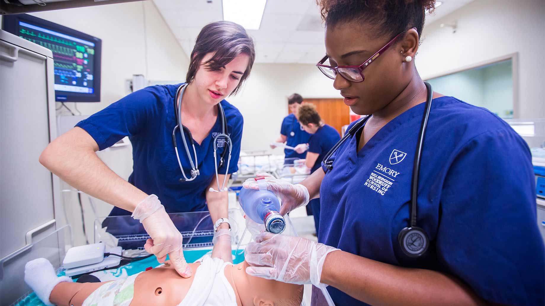 two female nursing students training with an infant mannequin