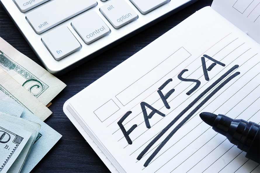 The word FAFSA written in a notebook with money and a calculator