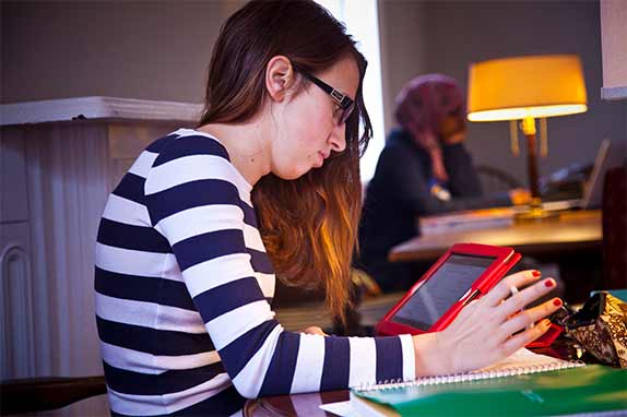 Student in striped shirt looking at red-colored iPad