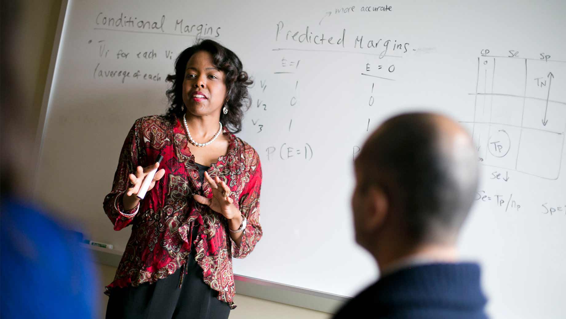 professor in red blouse in front of white board